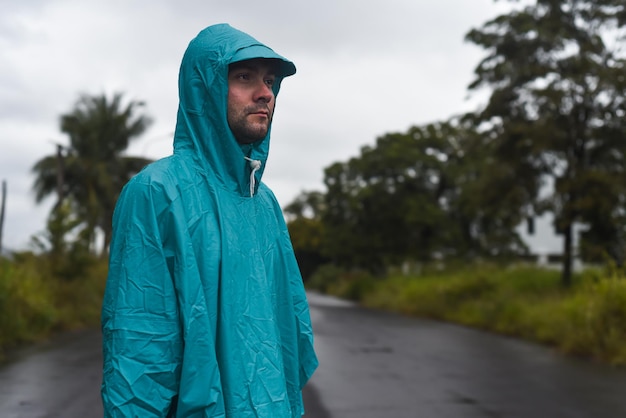 Depressief concept met eenzame man in regenjas staande op natte weg onder regen close-up geïsoleerd