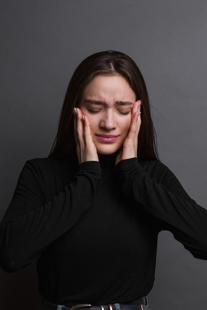 depressief jong meisje. Triest jonge vrouw in zwart shirt op donkergrijze achtergrond