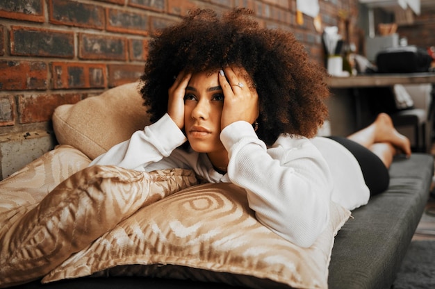 Depressief verdrietig en gefrustreerd Afrikaanse vrouw denken aan idee met angstprobleem met geestelijke gezondheid en depressie op de bank in huis Gefrustreerde angst en moe meisje met stress op huisbank