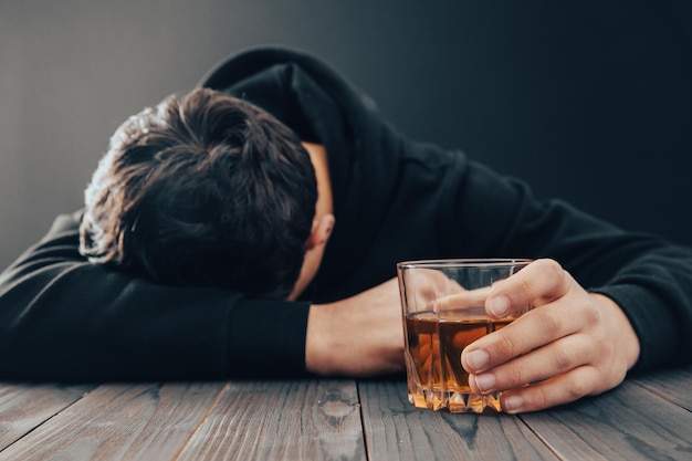 Foto depressieve man die binnenshuis alcohol drinkt