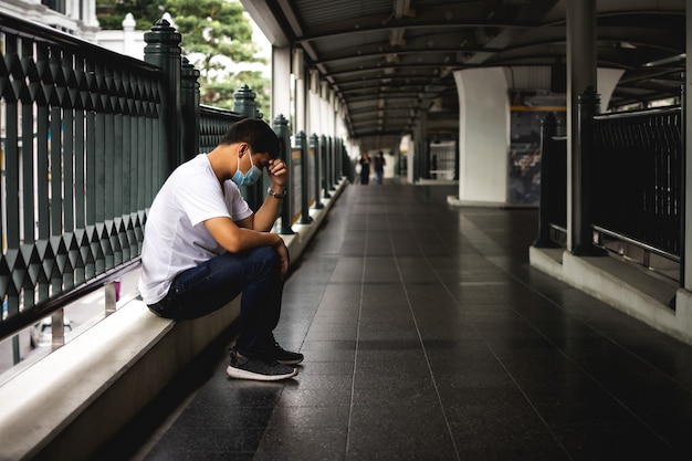 Depressieve man zit op de loopbrug van het pad van het hemeltreinstation Trieste man eenzaam en ongelukkig concept