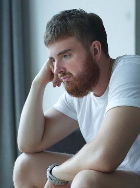 Foto depressieve ongelukkige trieste man van middelbare leeftijd die op de bank in de woonkamer zit en op zijn handen leunt