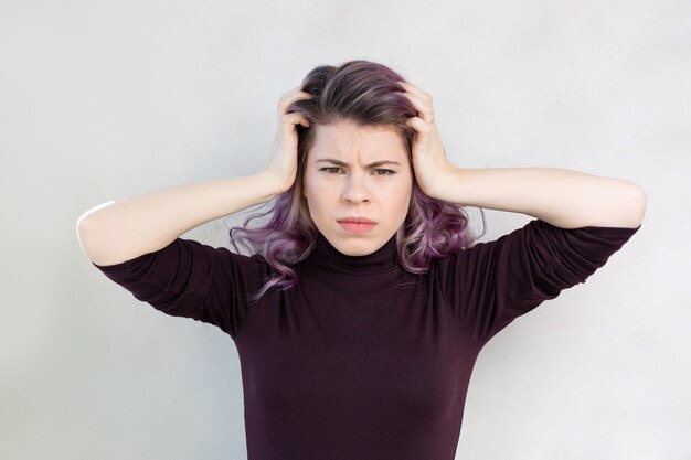 Depressieve overstuur vrouw met haar hoofd poserend over een grijze achtergrond