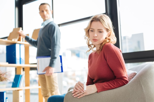 Depressieve stemming. Trieste sombere aardige vrouw die een tissue vasthoudt en gefocust is op haar gedachten tijdens een bezoek aan een psycholoog