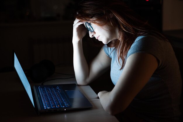 Depressieve vrouw met een laptop thuis.