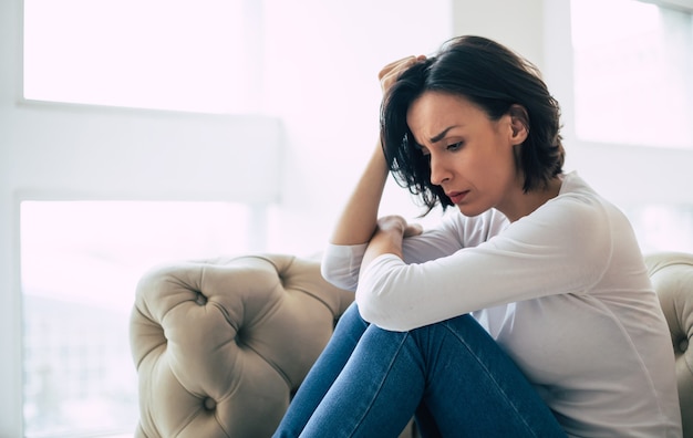 Depressieve vrouw met kort kapsel die huilt terwijl ze haar gezicht aanraakt. Meisje dat schreeuwt met haar ogen dicht vanwege haar psychische aandoening.