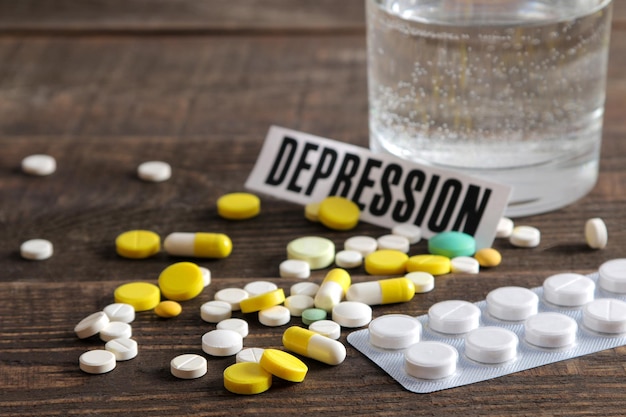 Depression concept a glass of water the inscription depression and pills on a wooden brown table