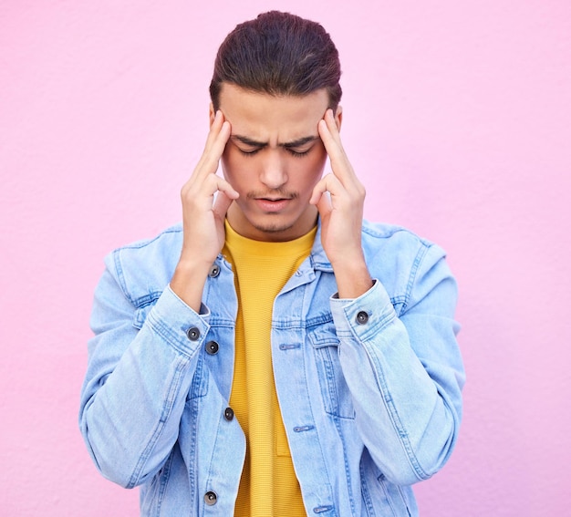 Depression stress and man with headache in studio isolated on a pink background Mental health anxiety and depressed unhappy or sad male model with problem pain or migraine burnout or fatigue