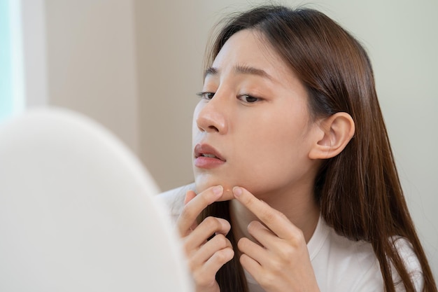 Dermatologia pubertà ragazza asiatica giovane donna che esamina l'allergia allo specchio quando si indossa la maschera e lo spettacolo cosmetico spremere il punto del brufolo per rimuovere dal visocura di bellezza dal problema della pelle con il trattamento dell'acne