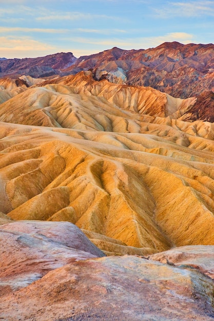 日の出の間のカラフルな堆積物の波の砂漠の山々