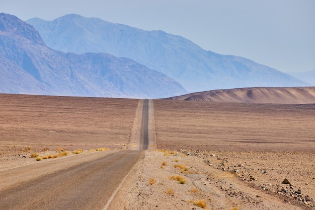 Пустынная дорога, идущая через пустынные холмы и равнины, ведущая к горам