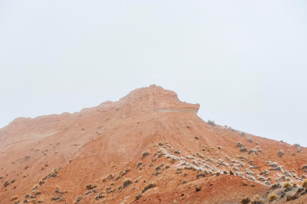 Desert with brown mountains partially covered with snow.