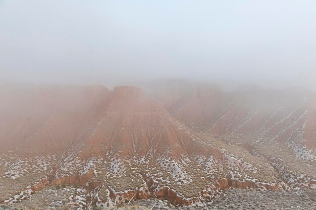 Desert with brown mountains partially covered with snow.