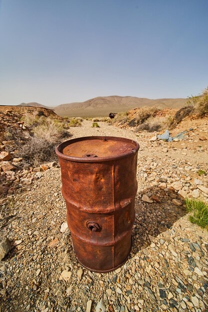 Desert with detail of large orange rusted mining barrel
