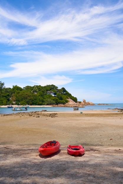 A deserted sandy beach on the beach with two red kayaks lying on it Vacation season in warm countries