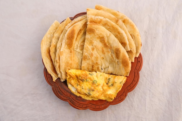 Desi breakfast egg omelet and paratha served in dish isolated on background top view of bangladesi breakfast