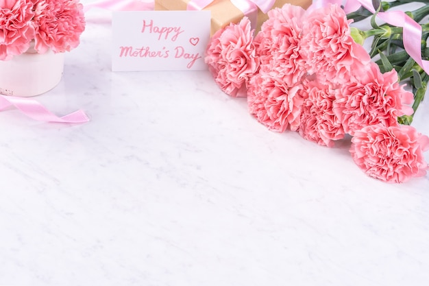 Design concept - Beautiful bunch of carnations on marble white background, top view, copy space, close up. Mothers day gift idea inspiration.