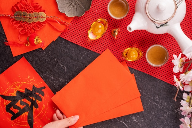 Design concept of Chinese lunar January new year - Woman holding, giving red envelopes (ang pow, hong bao) for lucky money, top view, flat lay, overhead above. The word 'chun' means coming spring.