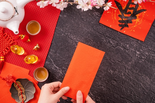 Design concept of Chinese lunar January new year Woman holding giving red envelopes ang pow hong bao for lucky money top view flat lay overhead above The word 'chun' means coming spring