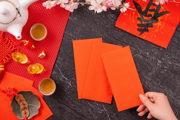 Concetto di design del nuovo anno lunare cinese di gennaio donna che tiene buste rosse ang pow hong bao per soldi fortunati vista dall'alto piatto sopra la testa la parola 'chun' significa primavera in arrivo