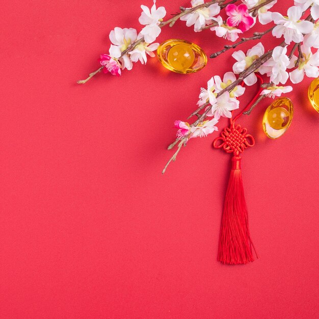 Design concept of chinese lunar new year - beautiful chinese\
knot with plum blossom isolated on red background, flat lay, top\
view, overhead layout.