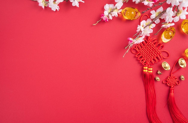 Design concept of Chinese lunar new year Beautiful Chinese knot with plum blossom isolated on red background flat lay top view overhead layout