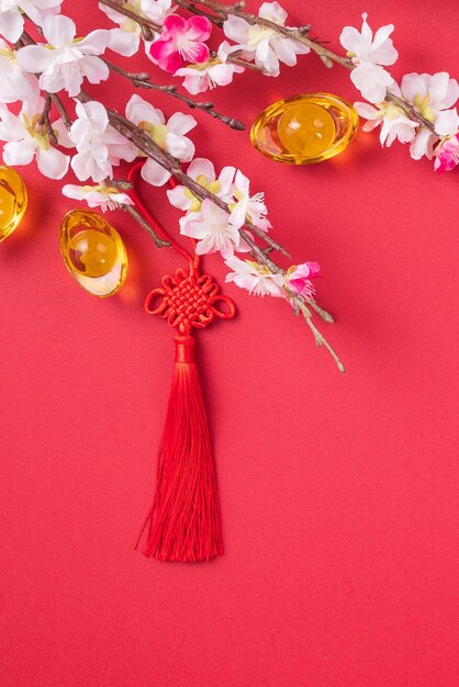 Photo design concept of chinese lunar new year beautiful chinese knot with plum blossom isolated on red background flat lay top view overhead layout