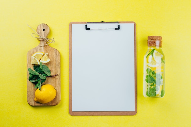 Design concept of mockup clip board and lemon mint water on yellow background. 