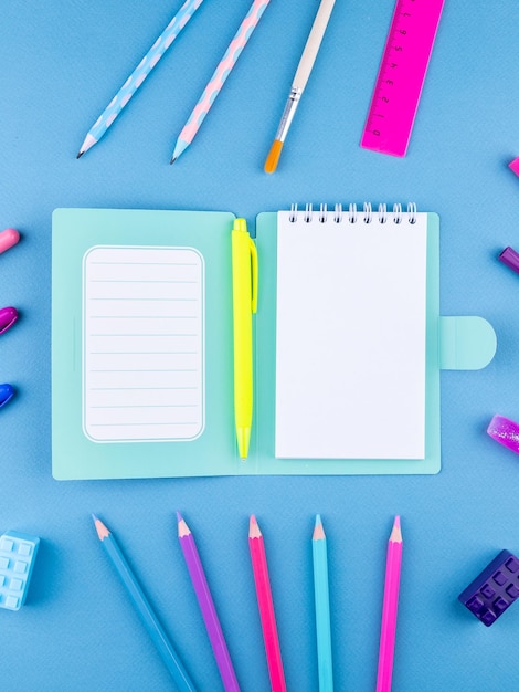 モックアップ用の青い背景に白いシートのブックマークバインダーとペンを備えたメモ帳のデザインコンセプトの上面図