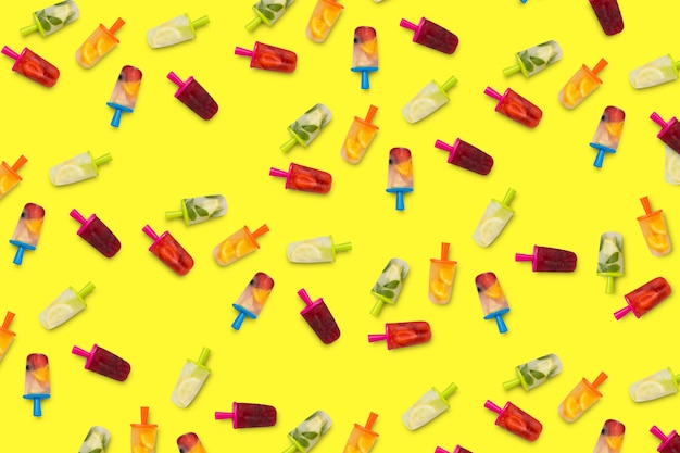 Design of fruit popsicles on a yellow surface.