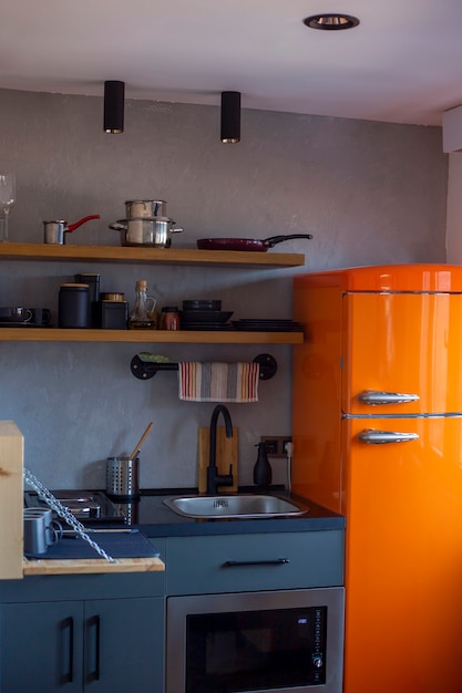 Design of small loftstyle kitchen with an orange refrigerator vertical orientation