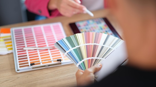 Designer advises his client to choose color from different samples in design studio closeup of