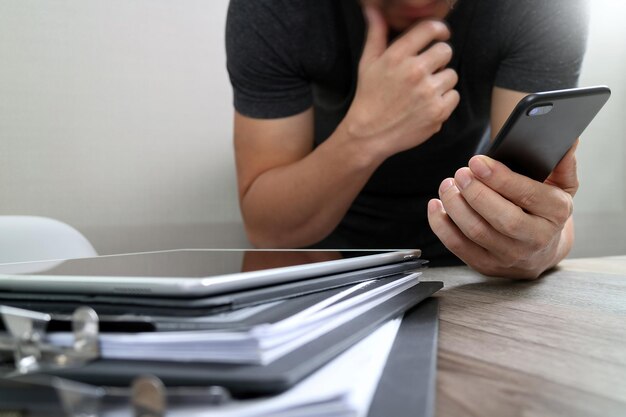 Designer hand using mobile payments online shopping in modern office wooden desk