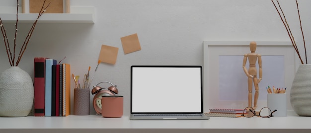 Designer huis met een laptop, boeken en decoraties op witte tafel