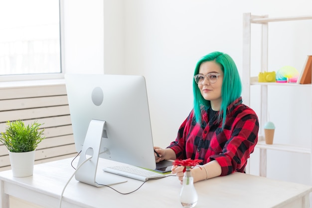 Designer, illustrator, artist and people concept - portrait of contemporary young woman with green hair using laptop and graphic tablet while working.