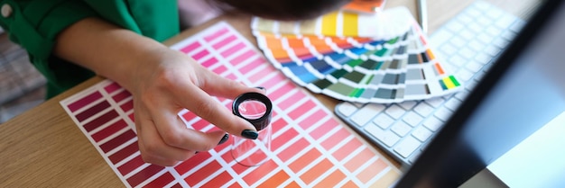 Designer looks through magnifying glass at samples of colors and shades of red on paper palette