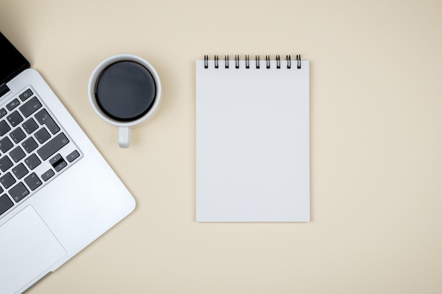 designer office desk with blank notebook page and laptop computer top view flat lay