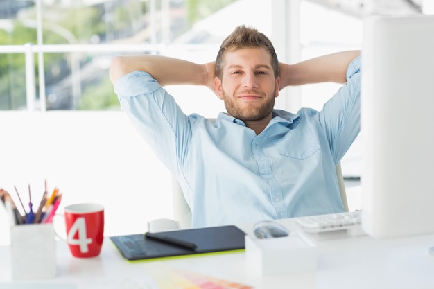 Designer relaxing at his desk smiling at camera