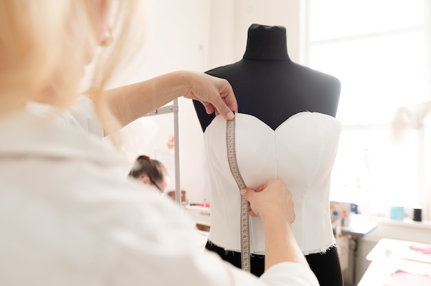 a designer who measures the fabric of the mannequin and marks the size length and shape of the item