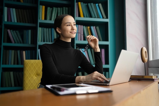 A designer with glasses works in a coworking space uses a
laptop and makes a report on the project