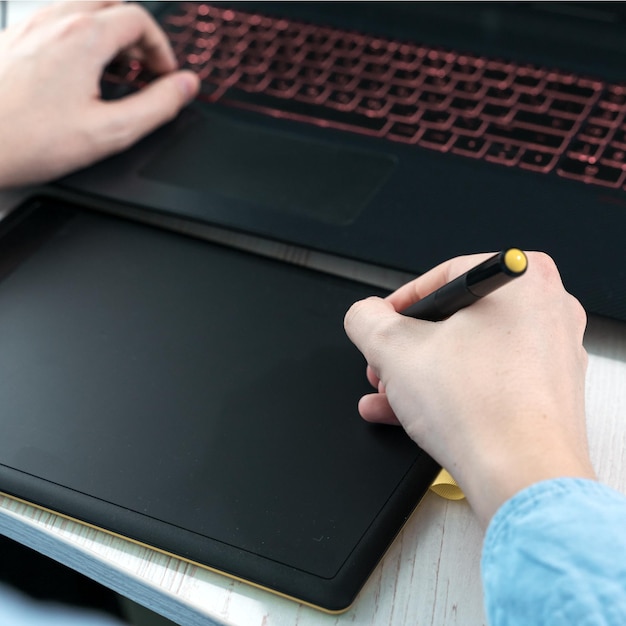 Designer working on a professional tablet with a pen Closeup of a mans hand holding a graphic pen for drawing