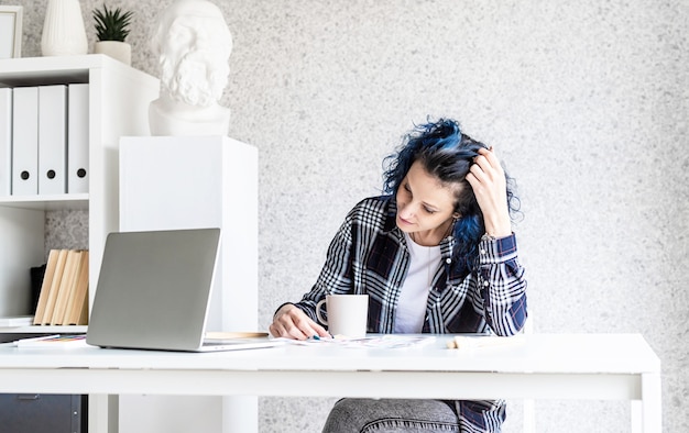 Designer che lavora con tavolozze di colori e laptop nel suo studio d'arte