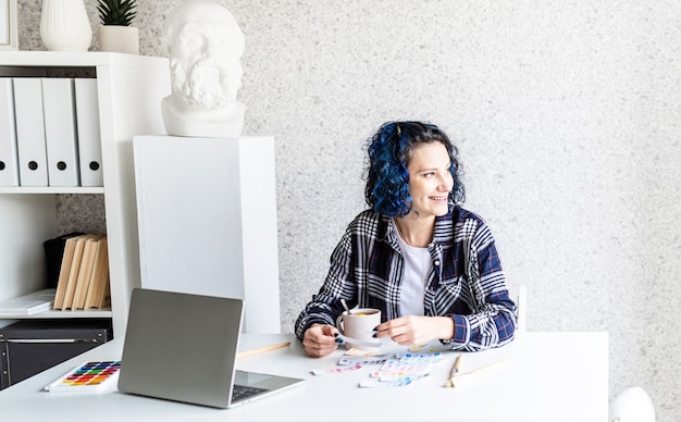 Designer working with colour palettes and laptop in her art studio