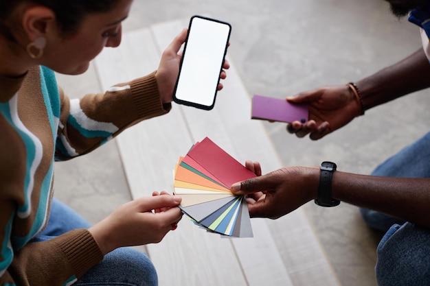 Photo designers using smartphone to choose color for flooring