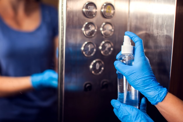 Desinfection of buttons in the elevator with antiseptic spray. Hygiene and virus protection concept