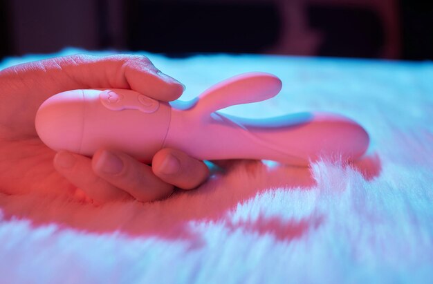 Desire concept Woman lying in bed holding a dildo vibrator in her hand to help herself