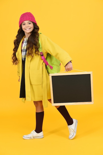 Desire for study. Here to Serve you. retro and modern school. small girl enjoy autumn. stylish schoolgirl blackboard. copy space for ad. happy pupil kid yellow wall. back to school.
