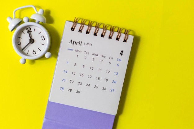 Desk calendar for April 2024 and clock on a yellow background