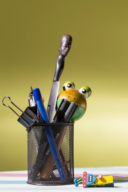 Desk objects in an openwork metal vase on the floor a colored clip