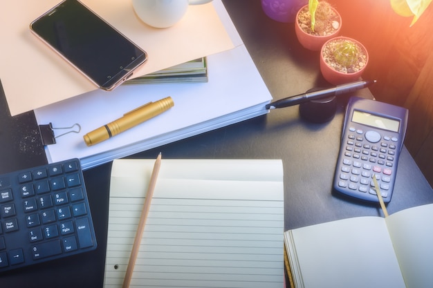 Desk, paper, books, notebooks, calculators. Cactus Coffee and keyboard. 